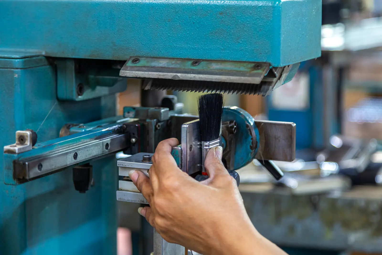 A worker's hand guiding a PETA brush into the trimming machine