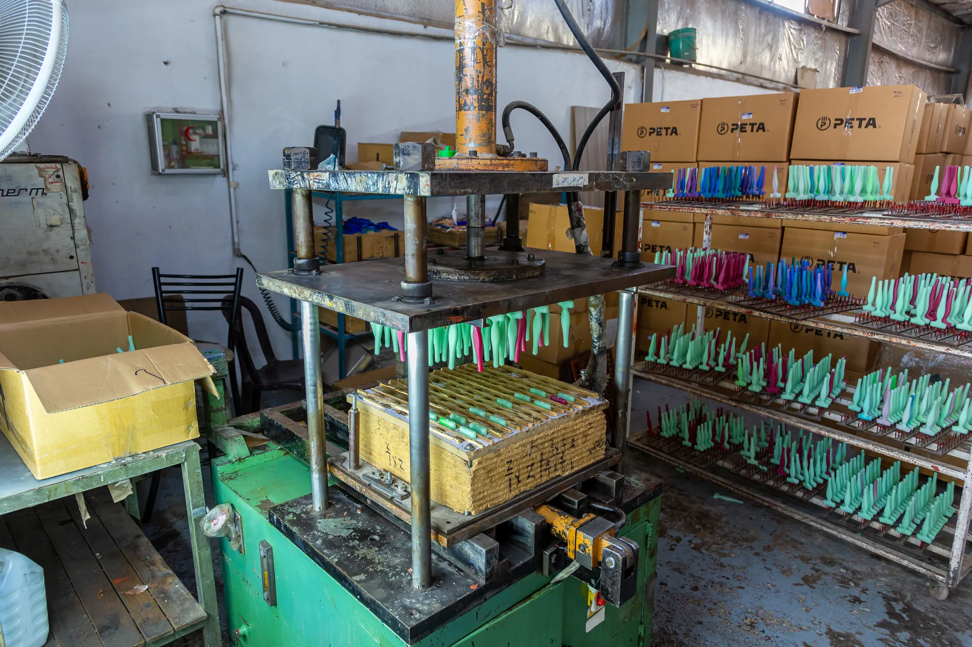 Green roller sleeves drying on racks beside stacked PETA-branded cartons